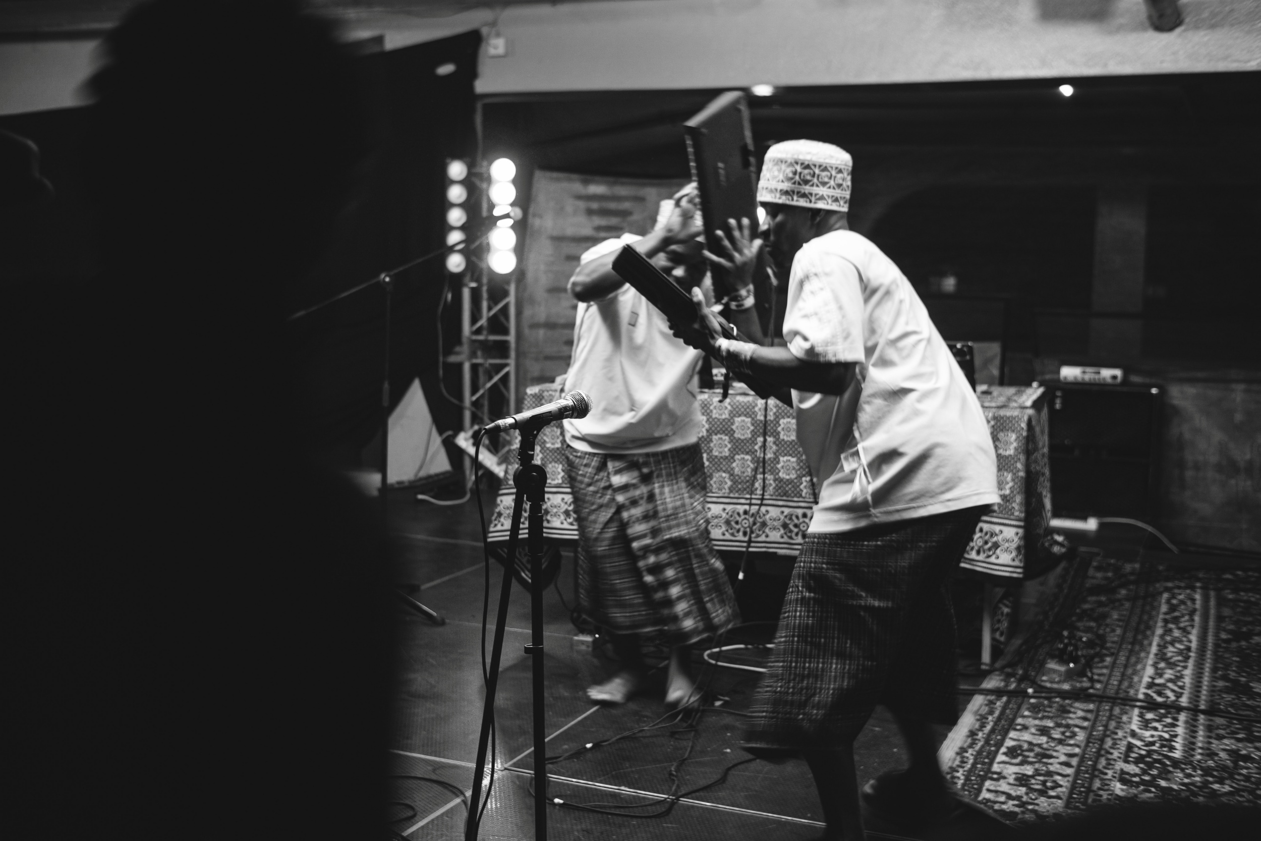 A black and white photo of two artists playing their instrument while dancing at the same time